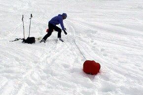 Person zieht an der Leine zum roten Ball im Schnee
